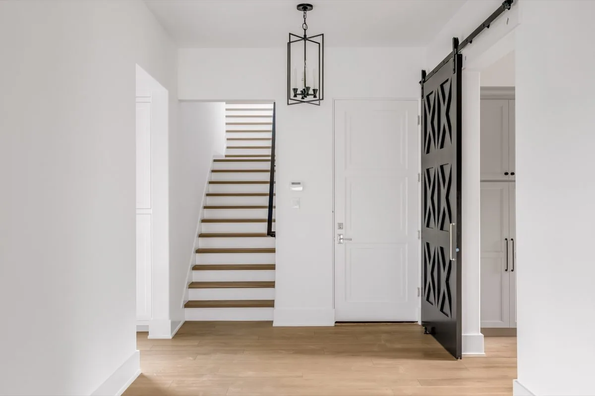 Entry hallway featuring wood floors, a black sliding barn door, and stairs with wood treads and white risers.