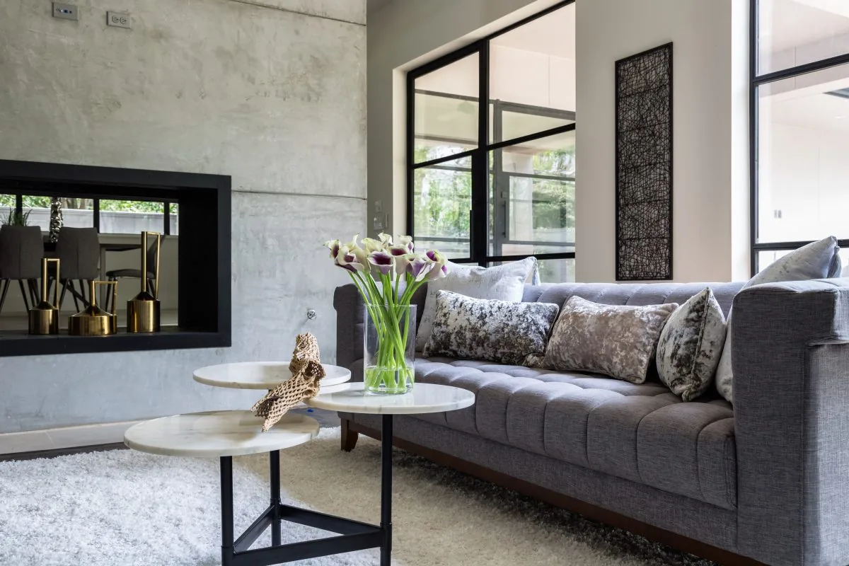 Living room features a gray sofa, white shag rug, marble nested coffee tables, and a black-framed recessed fireplace.