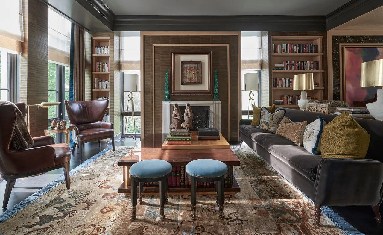 Living room features dark velvet sofa, leather armchairs, built-in bookshelves, and a decorative fireplace wall.