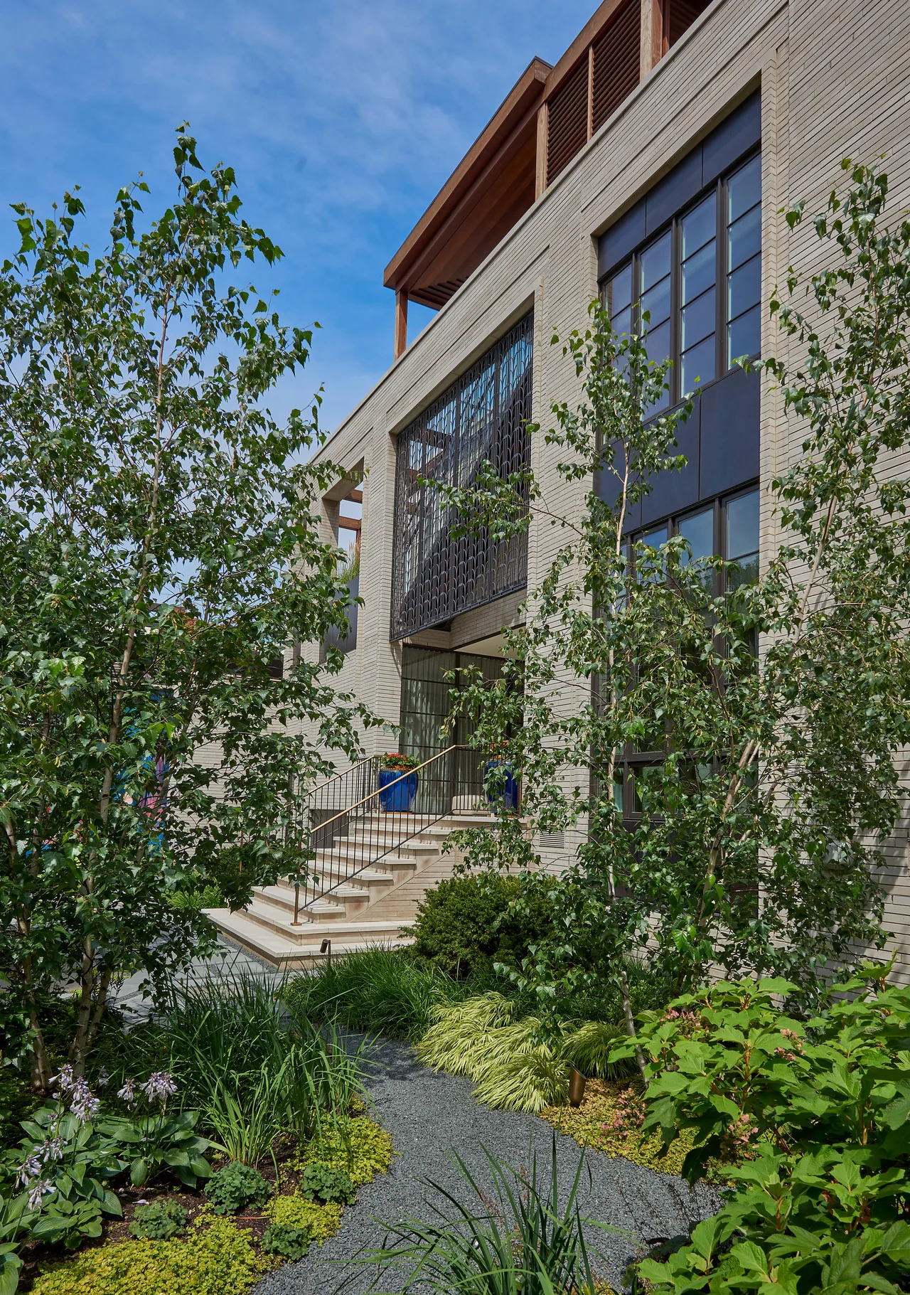 The Lakewood Residence features a symmetrical facade with ornamental metal railings, stone steps, and a landscaped front yard.