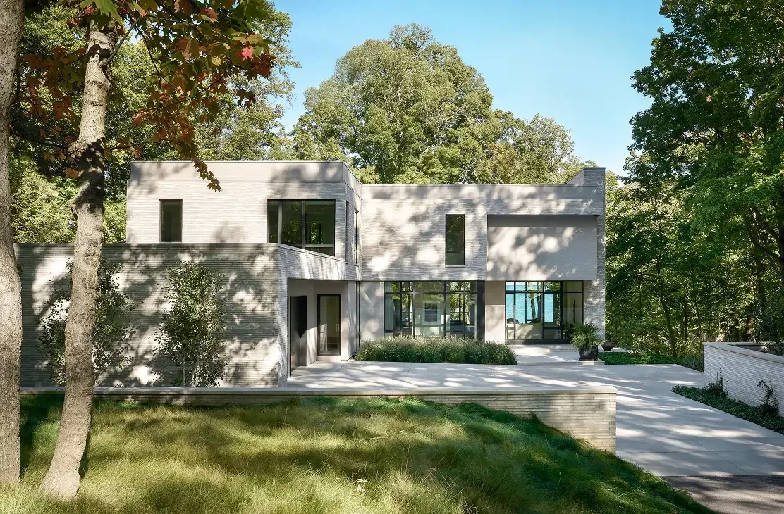 Ravine Reimagined by Jaffe Architecture features a modern white brick exterior with large black-framed windows and a flat roof.
