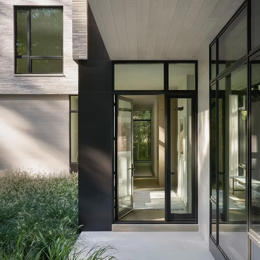 Front entry with floor-to-ceiling black-framed glass door and sidelights, featuring modern clean lines.