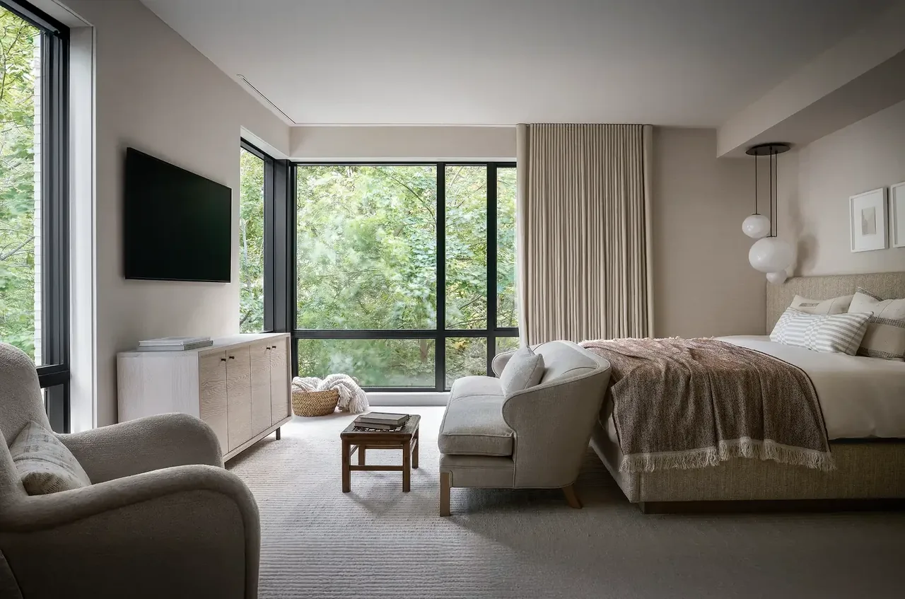 Bedroom in the Ravine Reimagined project features large corner windows and a neutral color palette.
