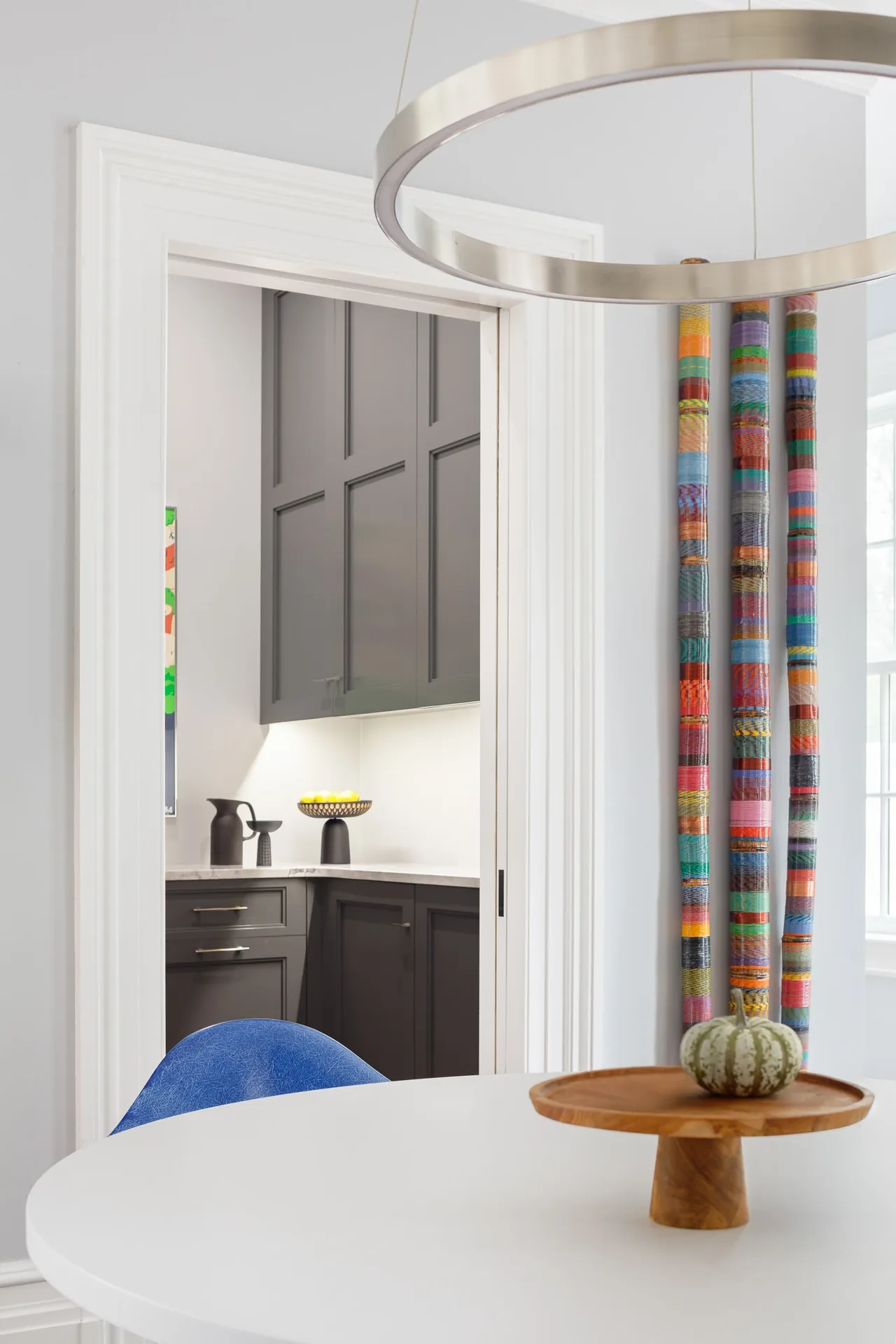 Dining area with a round white table and view into a kitchen featuring dark paneled cabinets.