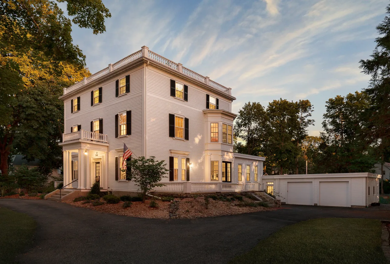 1870 Federal is a traditional three-story house with white siding, black shutters, and a detached garage, captured at sunset.