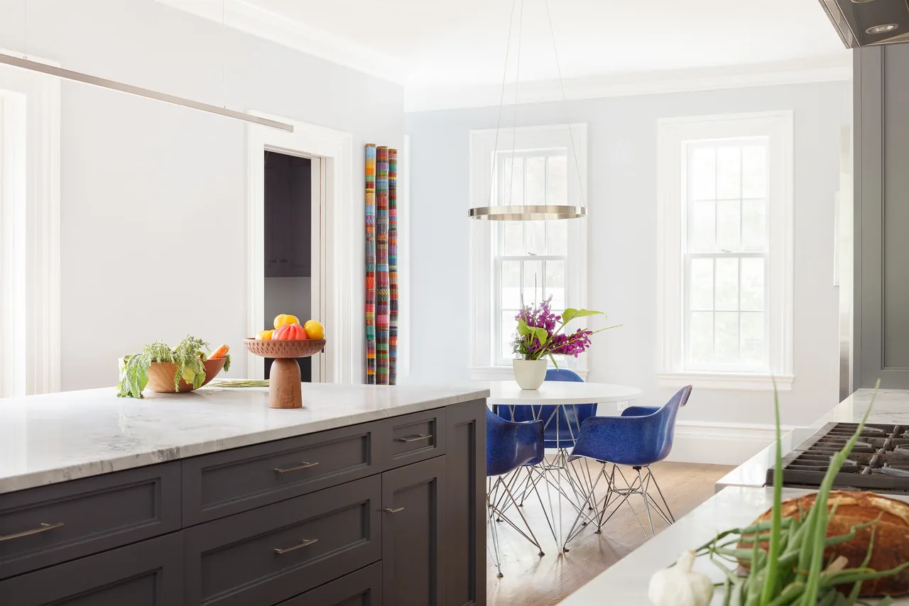 Kitchen and dining area with gray cabinetry, marble countertops, and blue dining chairs in 1870 Federal project.