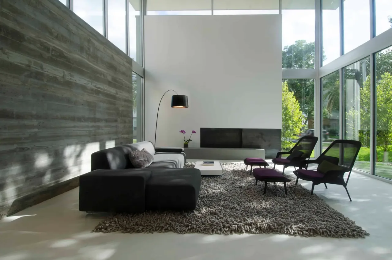 Living room in Jade house with floor-to-ceiling glazing and concrete wall by Intexure.