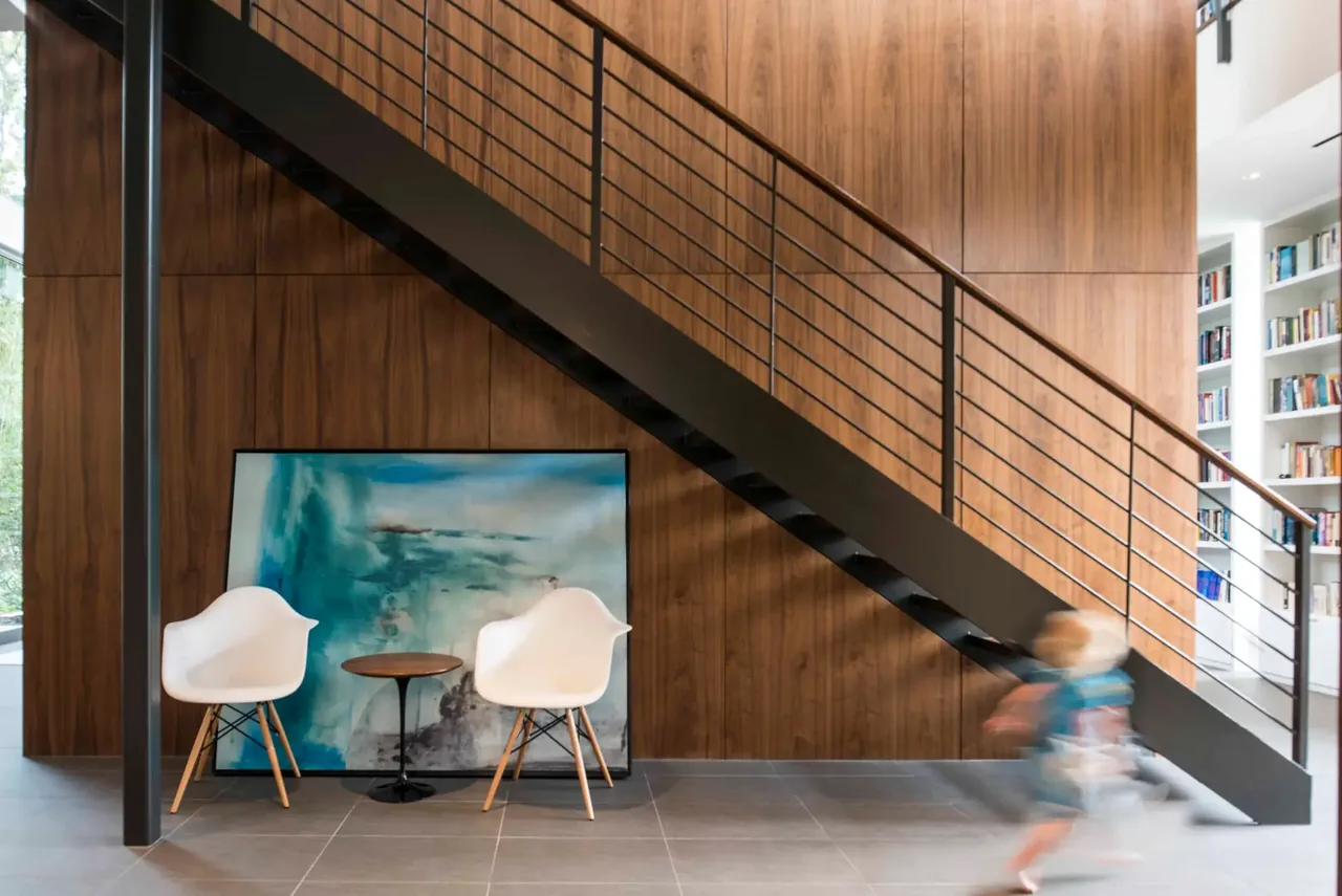 Modern interior featuring a black metal stair with wood panel wall and contemporary seating.