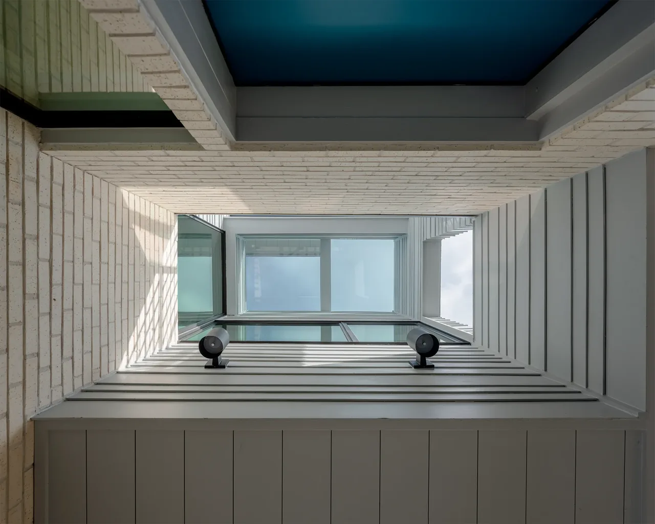 Vertical architectural shaft with white brick and horizontal siding walls at Windemere Residence.