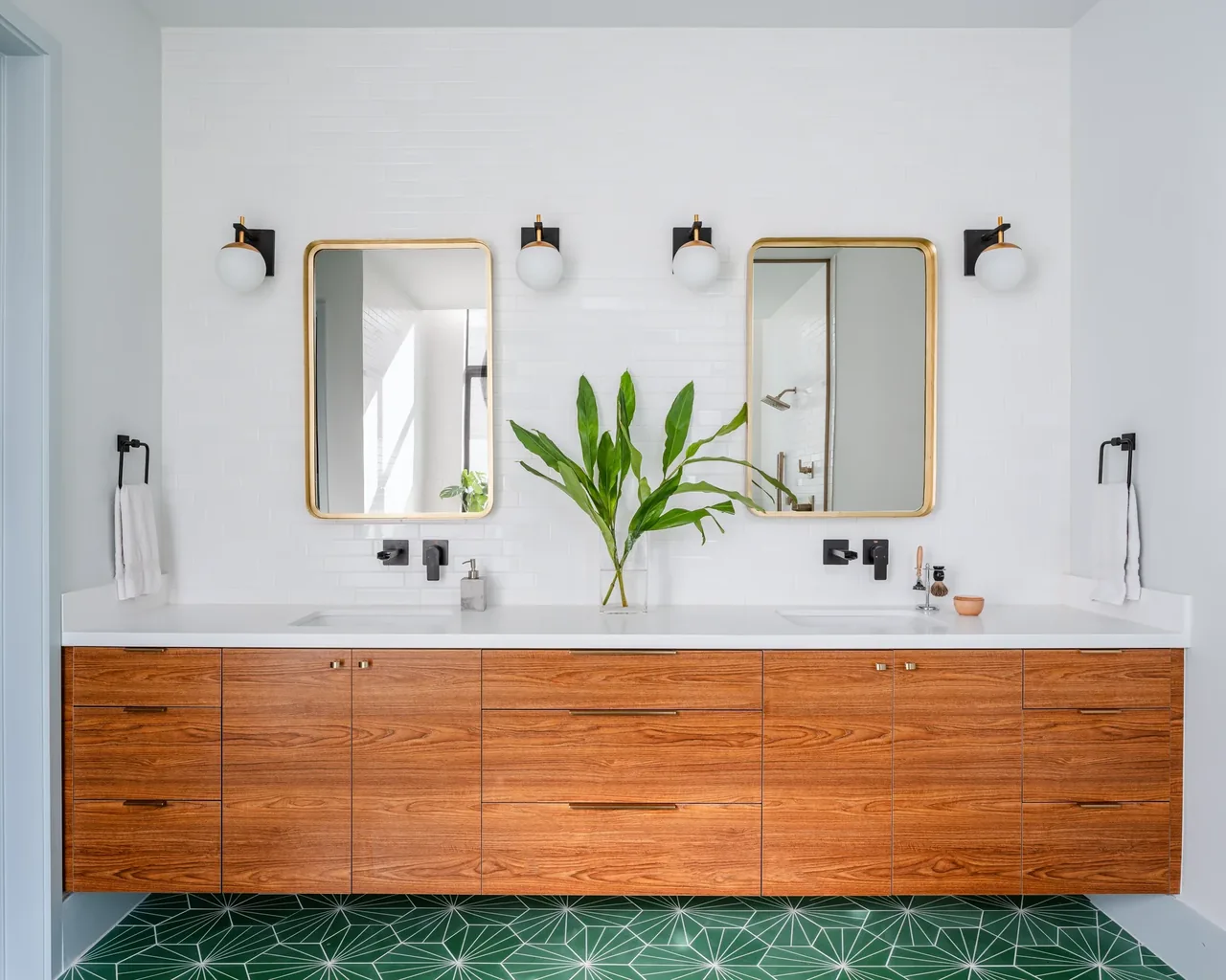 Bathroom vanity with floating wood cabinetry, dual sinks, and brass mirrors at Windemere Residence by Inflection Architecture in Houston.