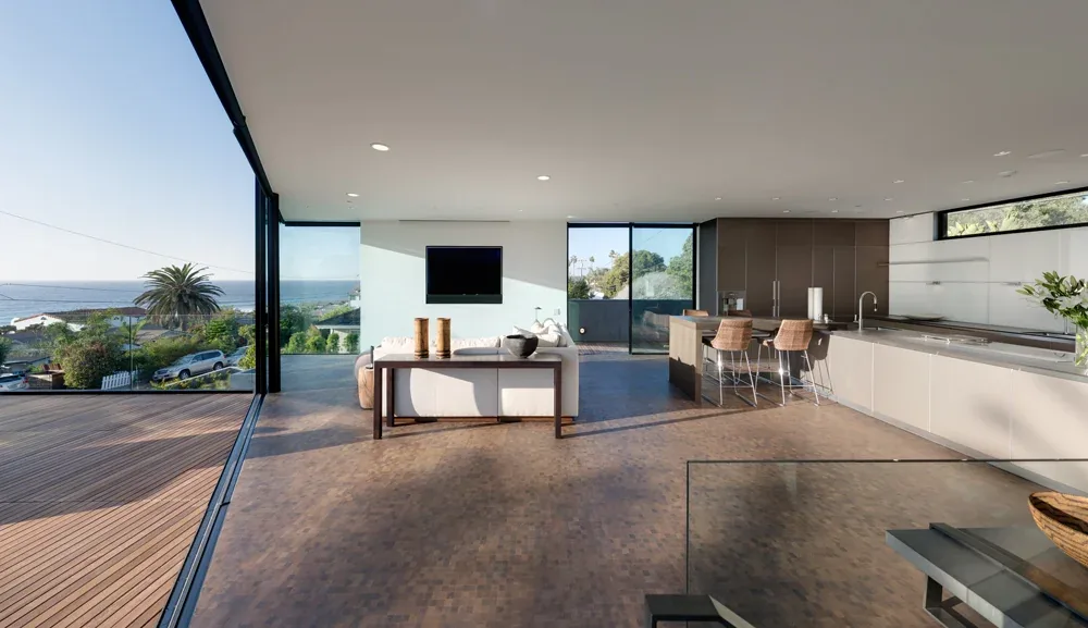Open living room and kitchen feature floor-to-ceiling glazing with ocean views and direct outdoor access.
