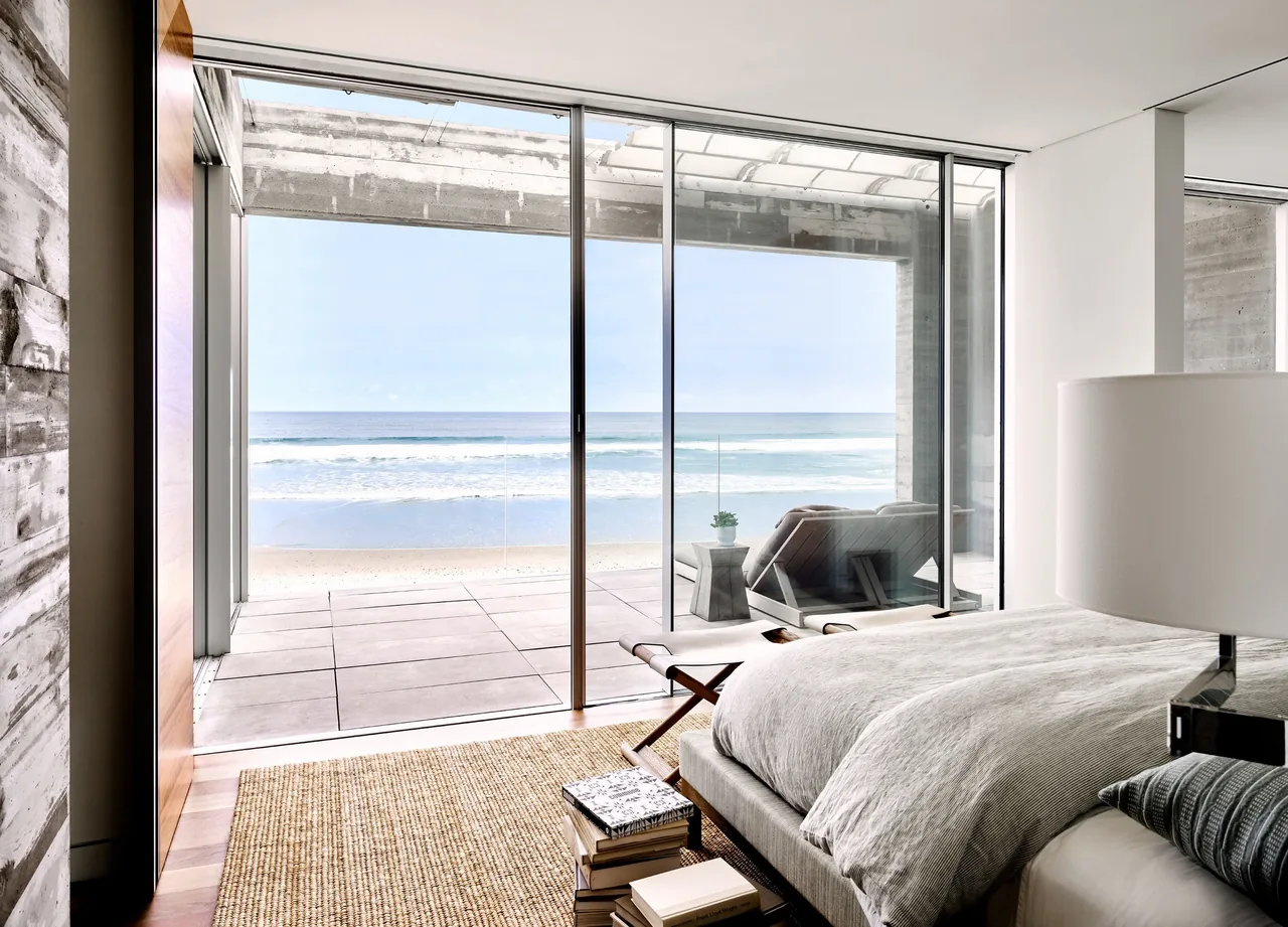 Bedroom featuring sliding glass doors that open to a patio with an ocean view.