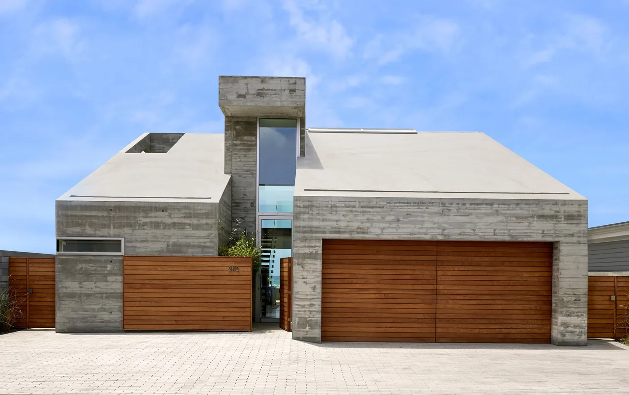 Levine House by Batter Kay Associates features raw concrete and horizontal wood siding with a flat roof.