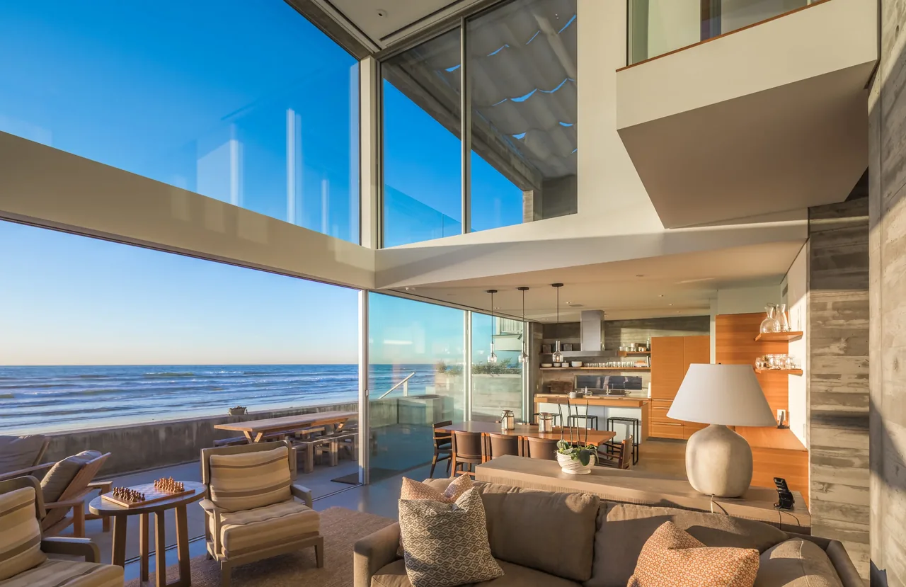 Open living and kitchen area with large glass windows offering ocean views in the Levine House by Batter Kay Associates.