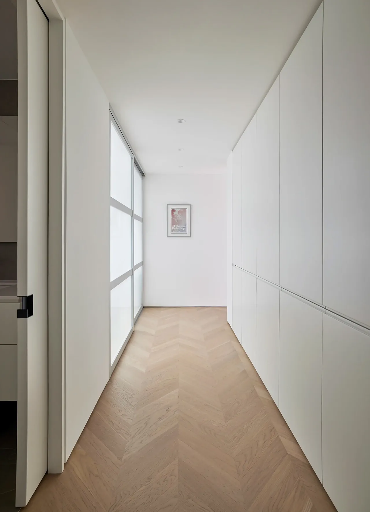 Minimal narrow hallway featuring herringbone wood flooring and extensive built-in white cabinetry