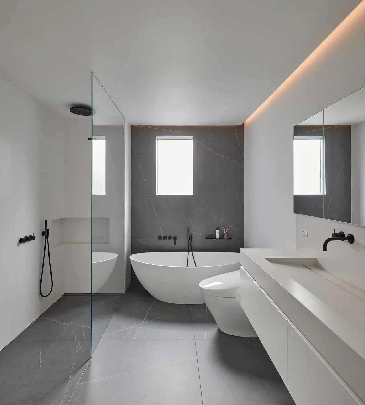 Bathroom features a freestanding bathtub, glass shower, and floating vanity with black fixtures.