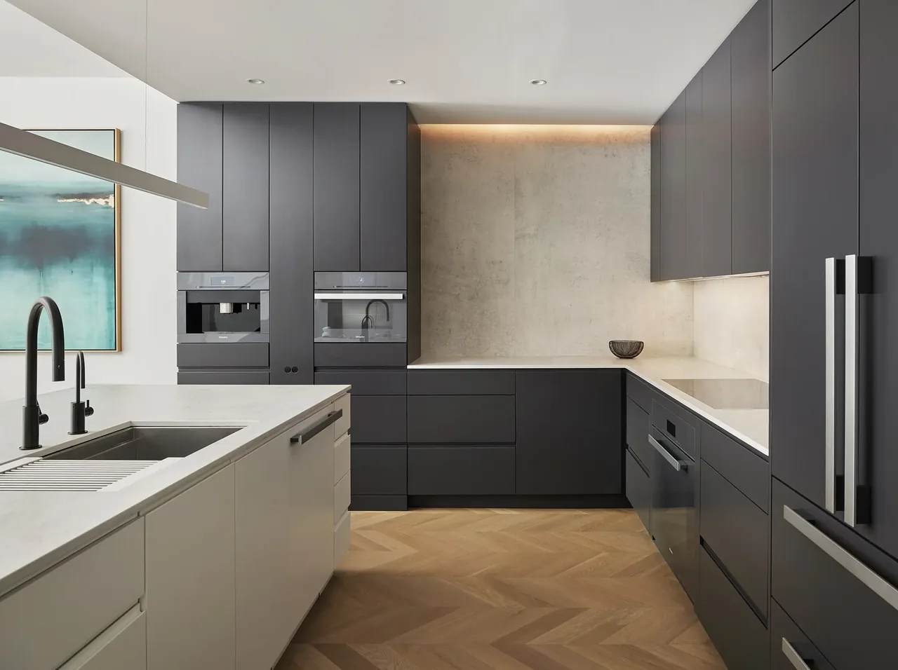 Kitchen features dark gray cabinetry, white countertops, built-in appliances, and a herringbone wood floor in a sleek modern design.