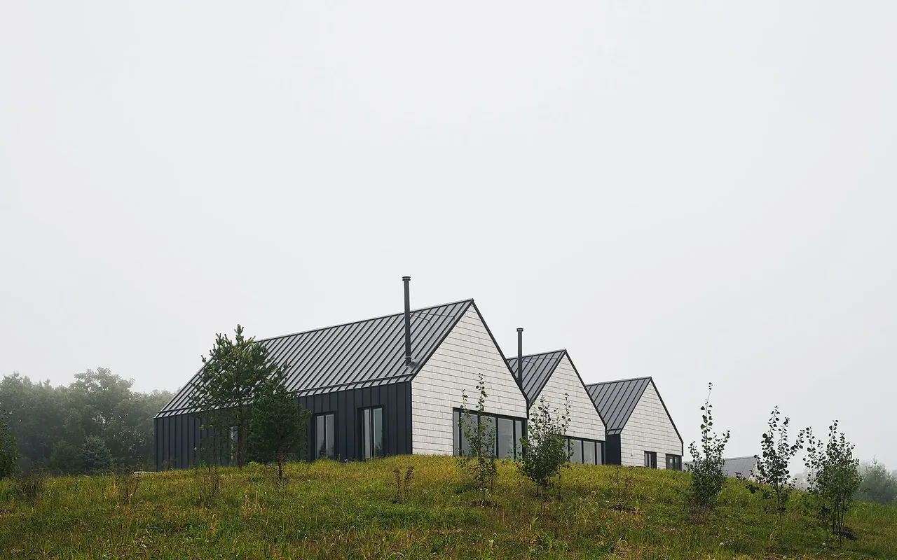 Lake Geneva House features connected pavilions with black standing seam metal roofing and beige shingle siding.