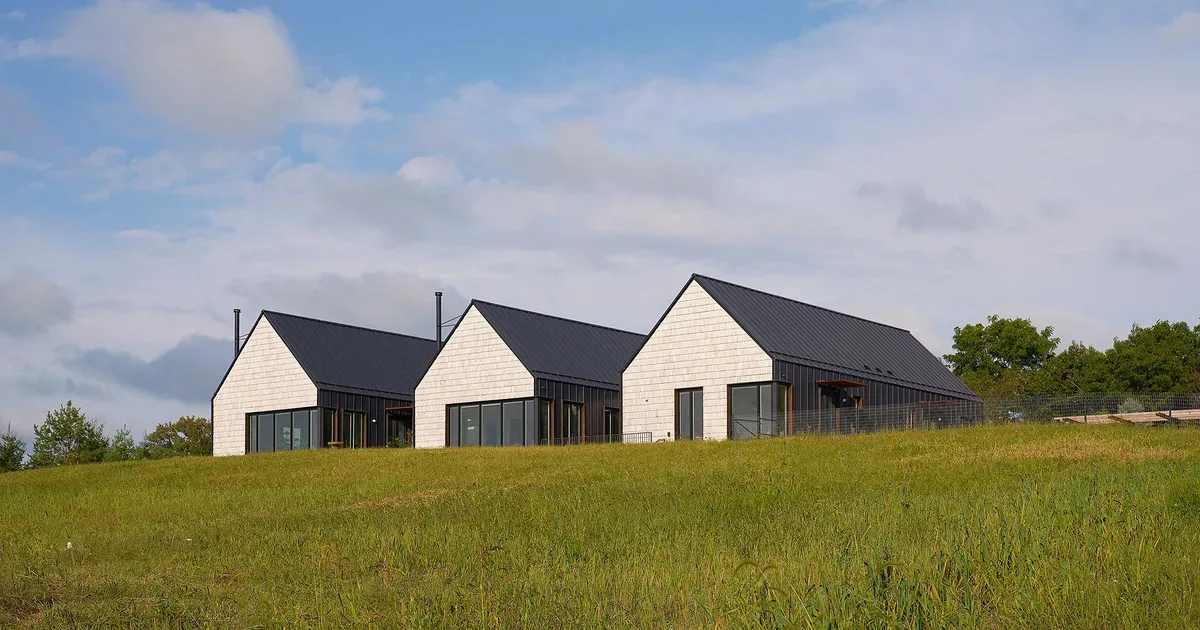 Lake Geneva House features three connected structures with gable roofs and contrasting light siding and dark metal roofing.