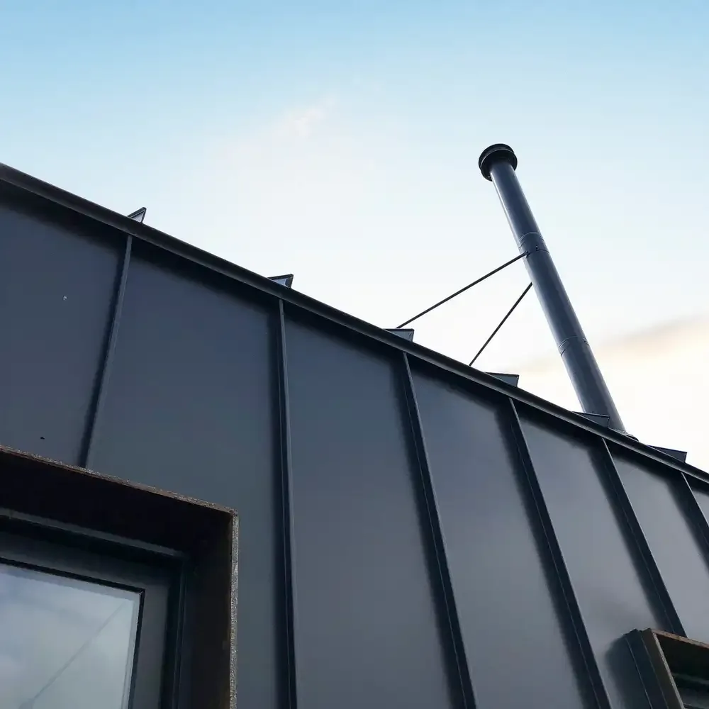 The Lake Geneva House features standing seam metal roofing and a chimney with support cables.