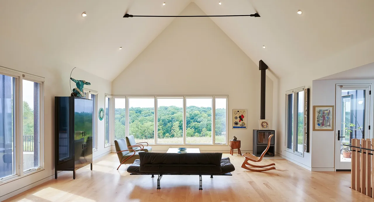 Living room with vaulted ceiling, large picture window, wood flooring, and black leather sofa at Lake Geneva House.