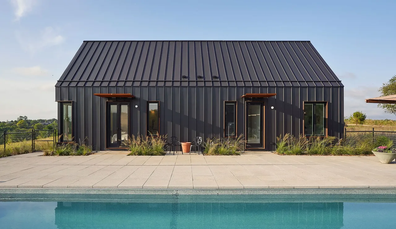 Lake Geneva House features a black metal siding building with rectangular windows and a gable roof facing the pool patio.