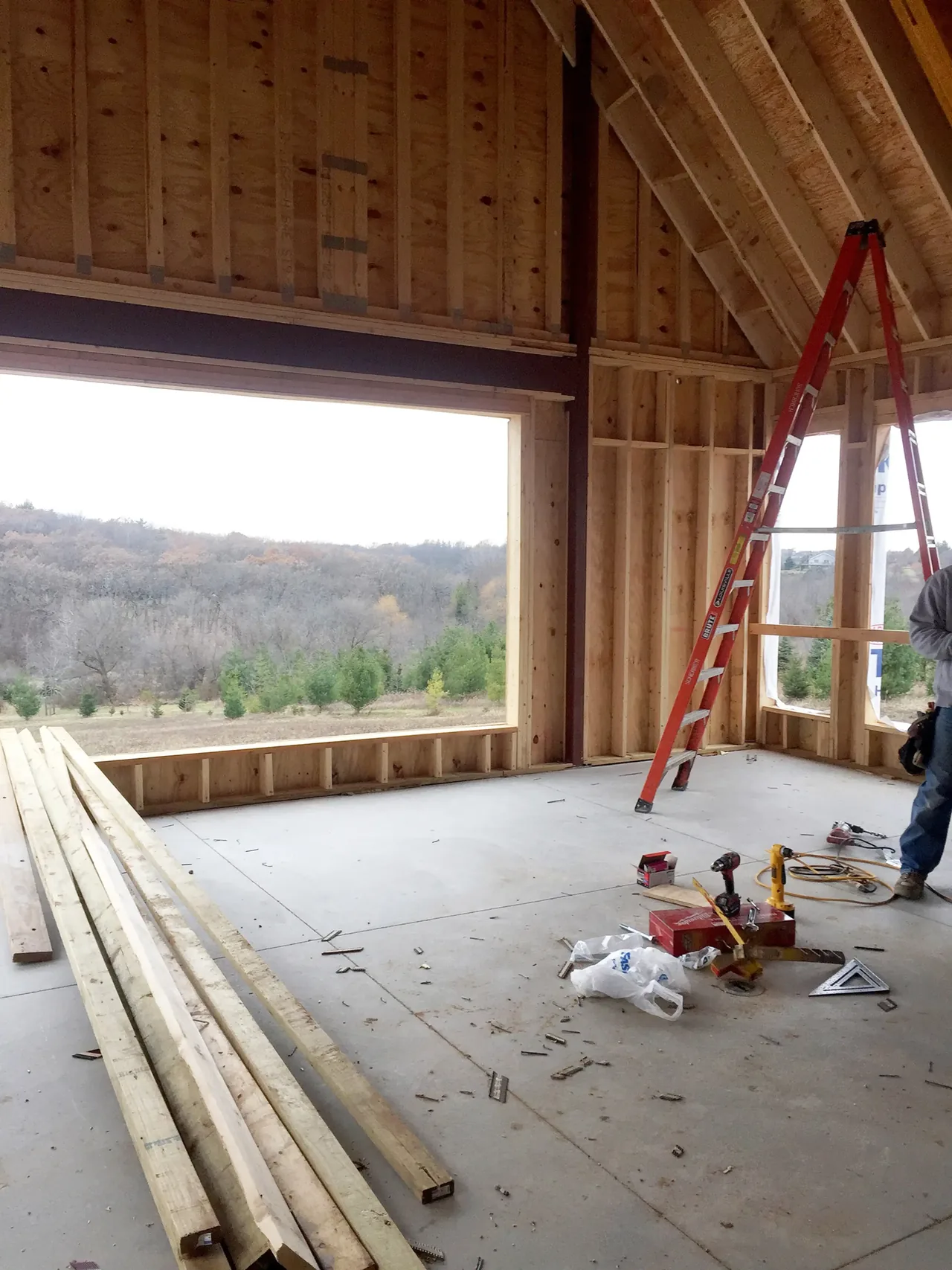 Unfinished interior space with exposed wood framing and large rectangular window openings during construction phase.