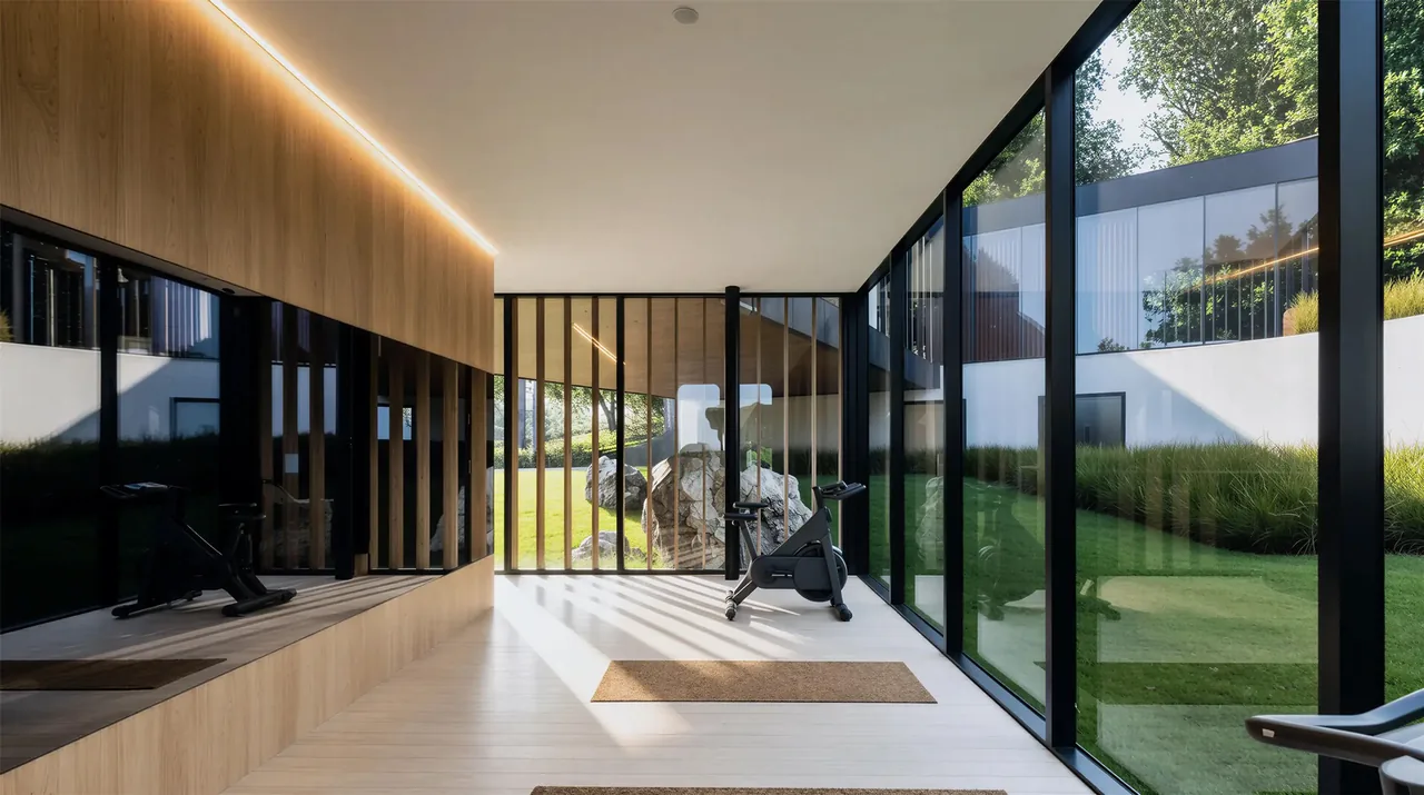 Indoor gym room in the Lakeside House features floor-to-ceiling black window frames and views of the integrated landscape outside.