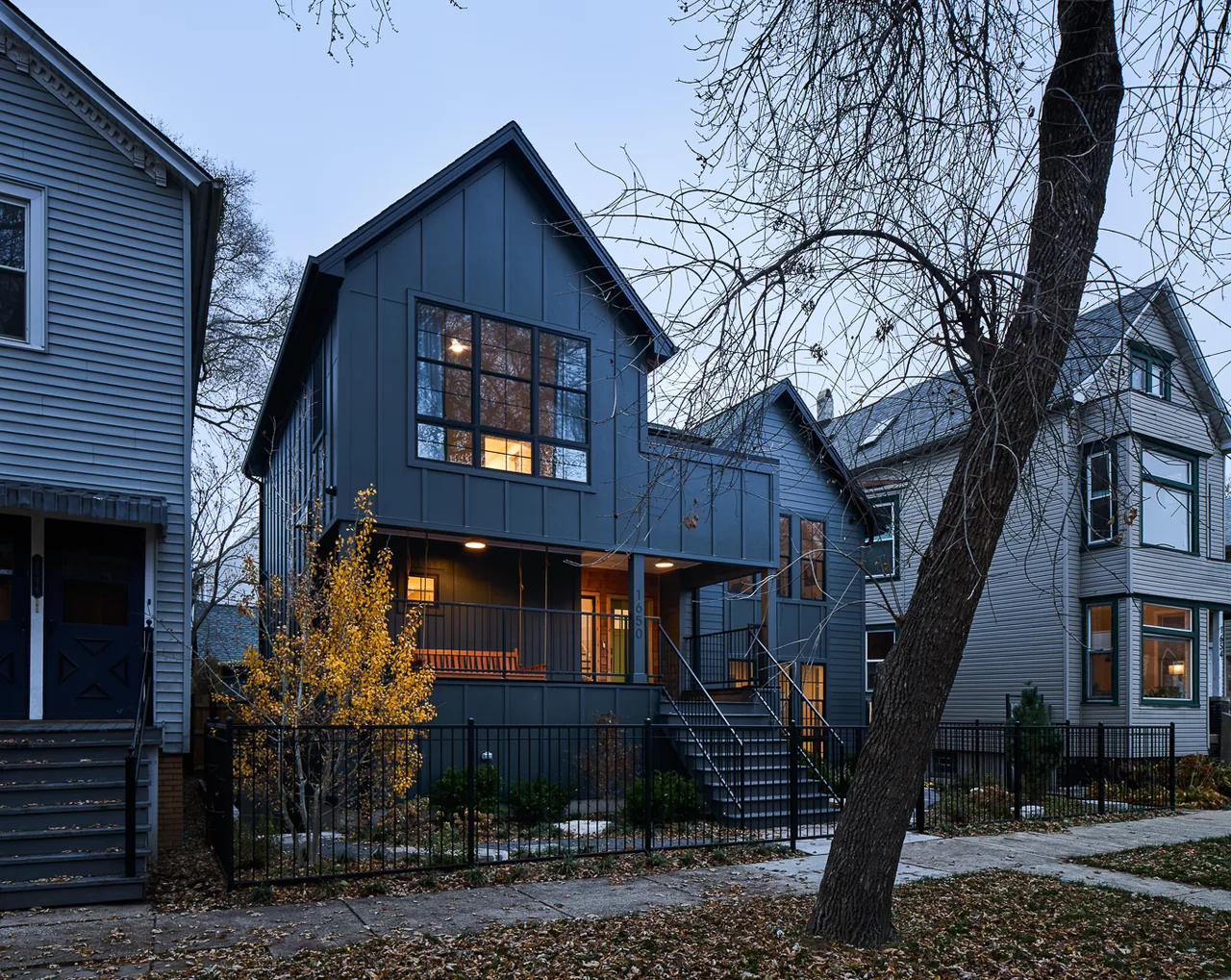 The Mozart House features a two-story modern design with a front porch and metal fence around the yard.