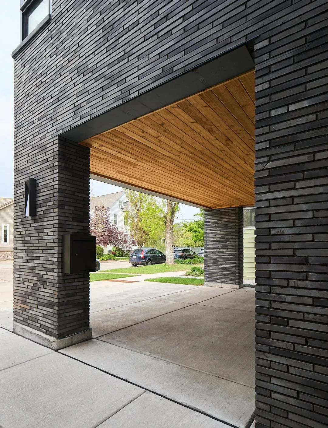 The Cullom House features an open garage with a dark brick facade and wood-paneled ceiling.