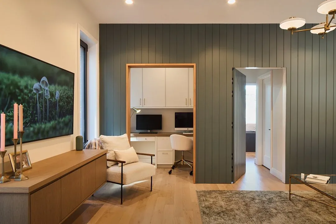 Living area features light wood floors, a medium wood console, and doorway to a home office with built-in white cabinetry.