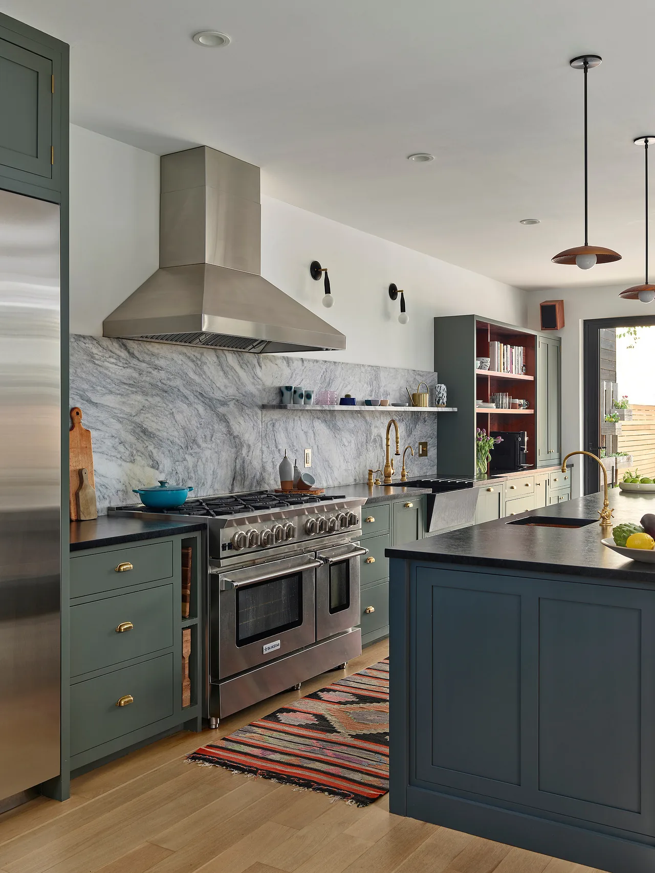 Kitchen features green cabinets, stainless steel appliances, a marble backsplash, and pendant lighting over the island.