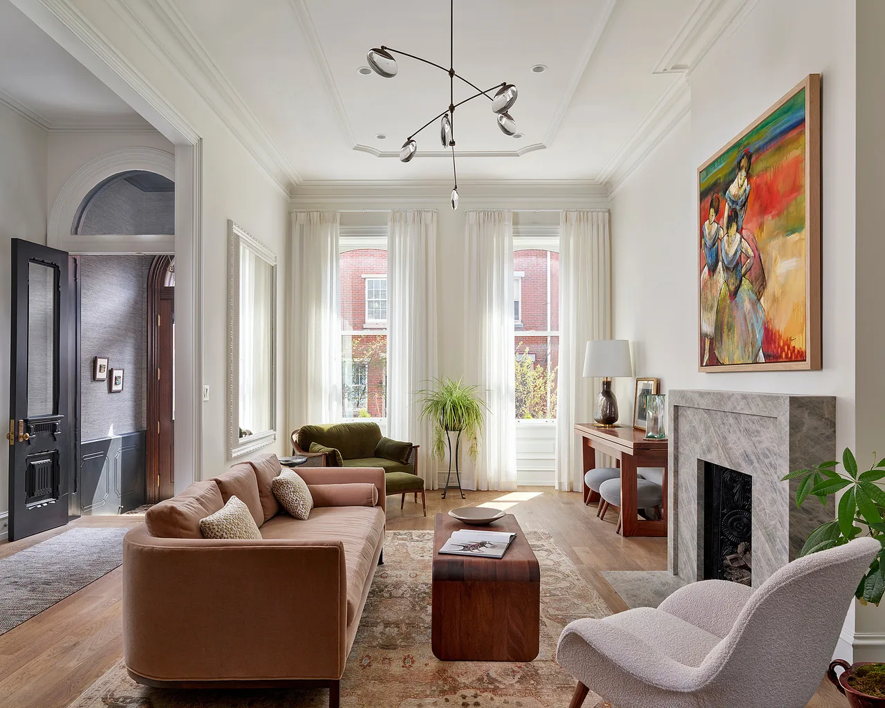 Light-filled living room with marble fireplace surround and wall art of dancers in the Fitler Square Renovation by Wyant Architecture.
