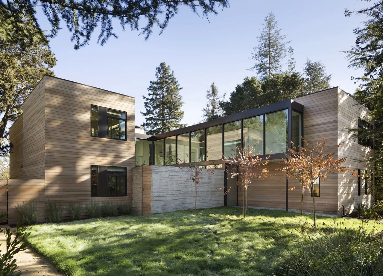 Hermosa Residence features horizontal wood siding and a glass connecting bridge between two blocks.