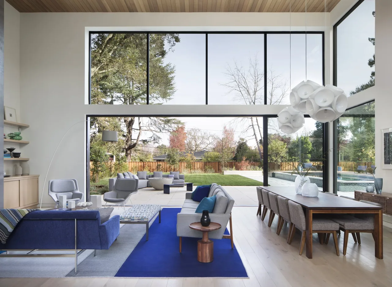 Hermosa Residence features an open living and dining space with floor-to-ceiling glazing that connects indoors to outdoor living and pool area.