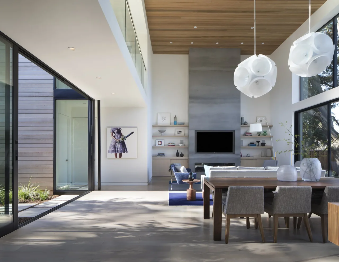The Hermosa Residence features an open living and dining space with a concrete accent fireplace and large glass walls.