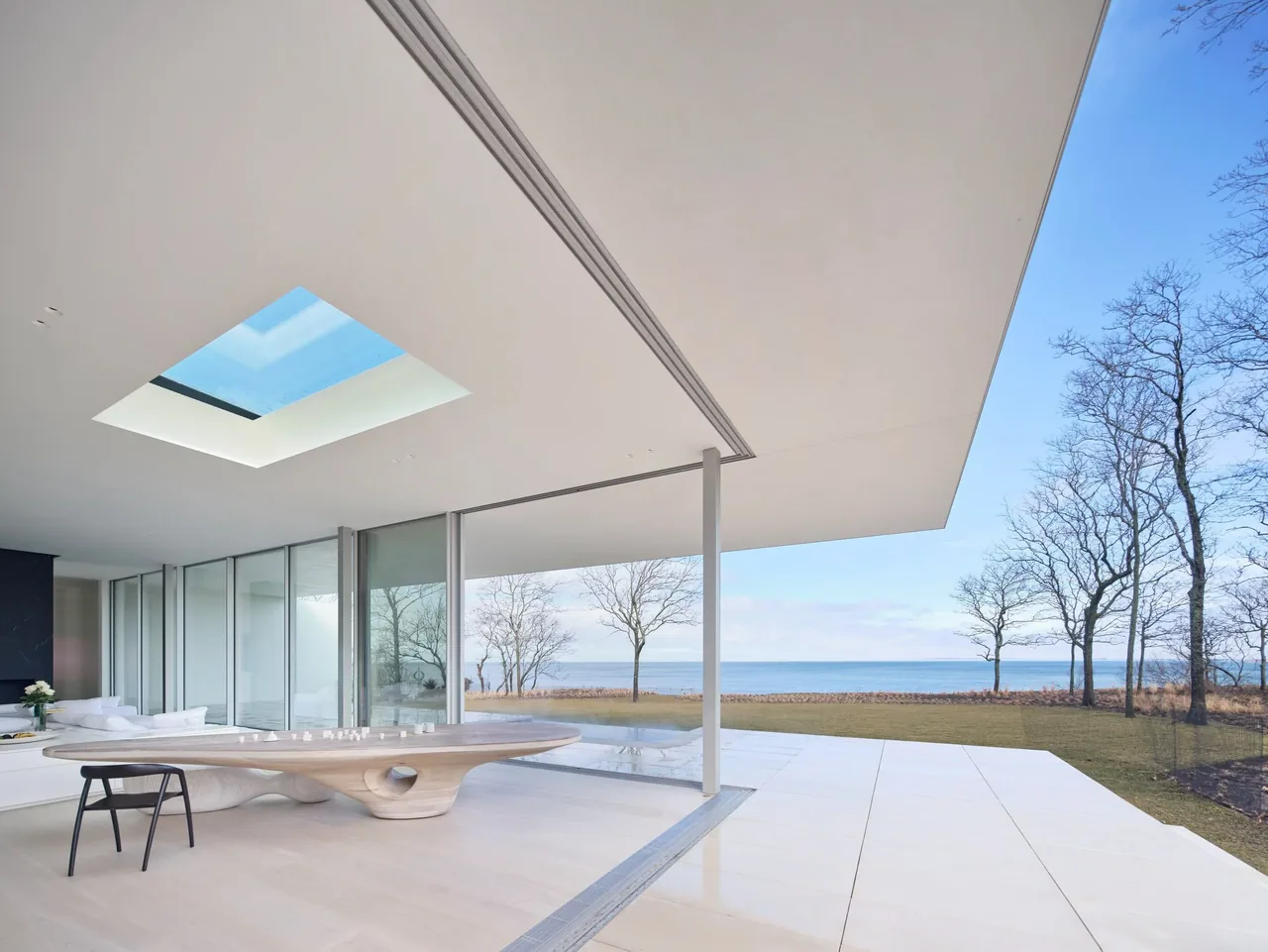 Open living space featuring a skylight and floor-to-ceiling glass walls with views to the water.