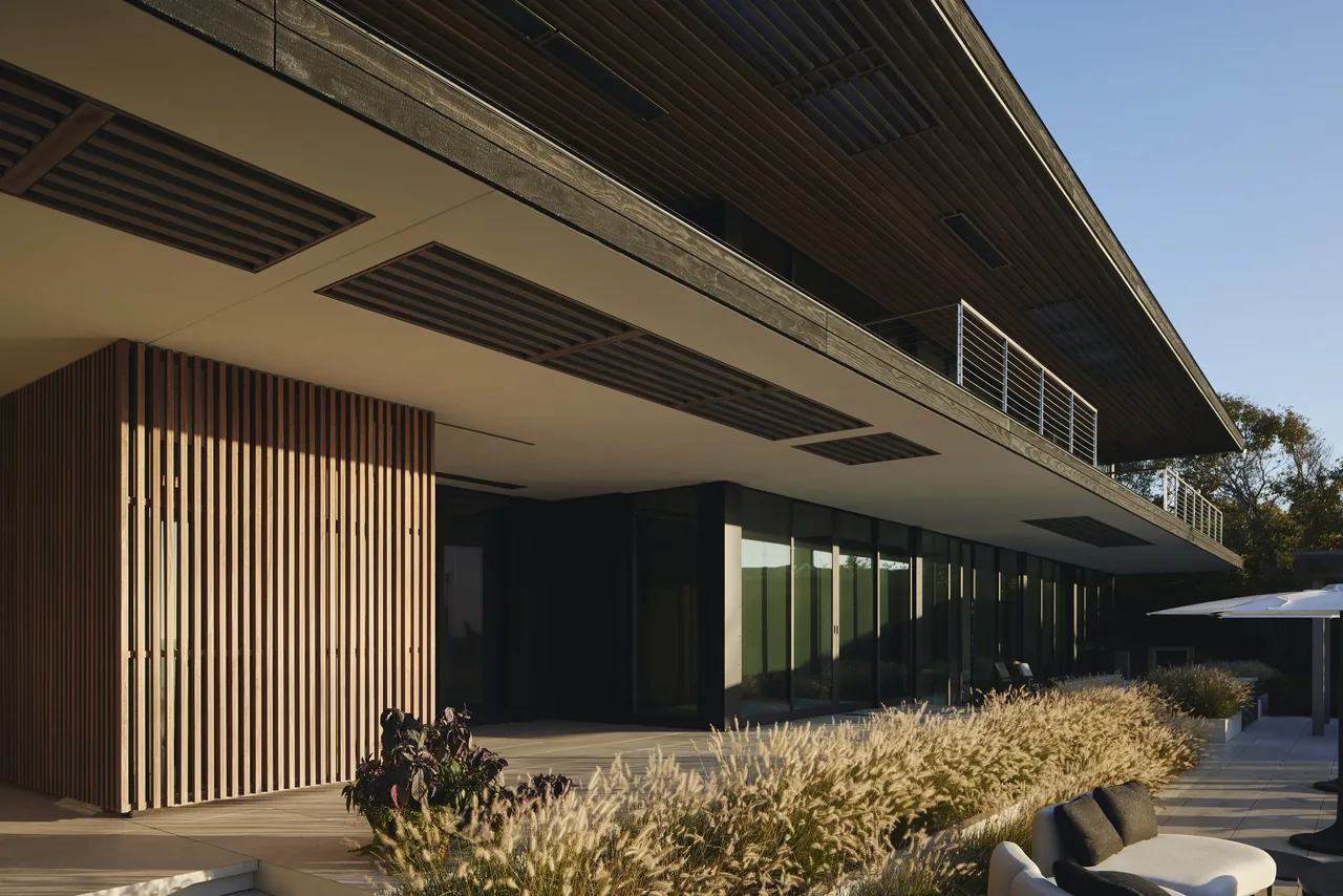 The Ocean Bluff residence features horizontal wood siding, vertical wood slat screens, and extensive floor-to-ceiling glazing.