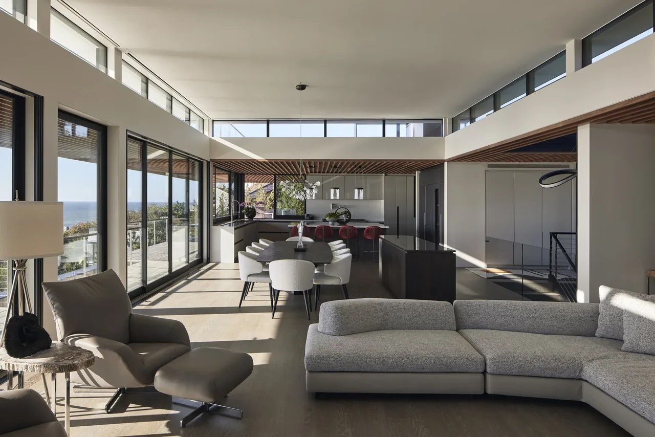 Open-concept living and dining area with floor-to-ceiling glazing and high clerestory windows overlooking the ocean at Ocean Bluff.