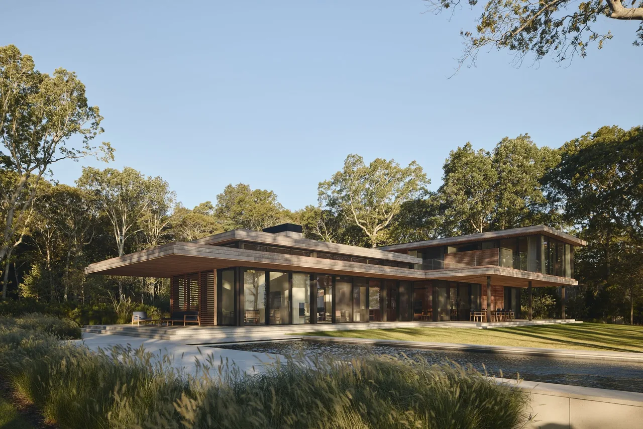 Contemporary two-story home features floor-to-ceiling glazing and horizontal wood siding with integrated landscaping by a pool.