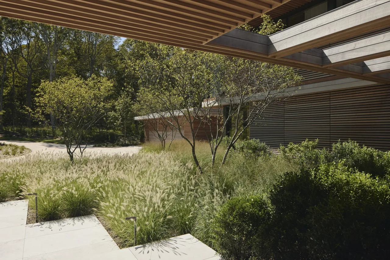 Exterior view showing horizontal wood slat walls and ceiling features integrated with landscaped greenery.