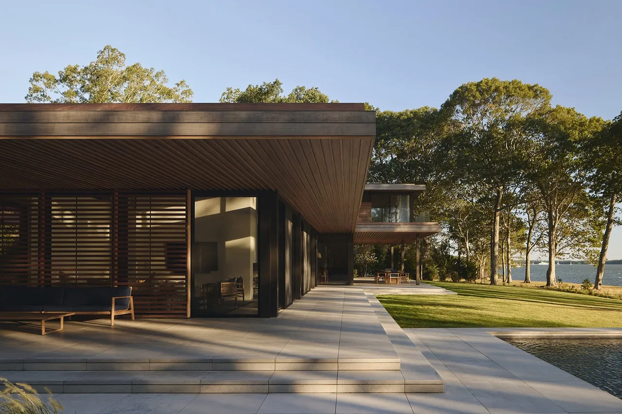 Contemporary facade of FOREST EDGE with horizontal wood slats, a reflective pool, and integrated landscaping by Stelle Architects.