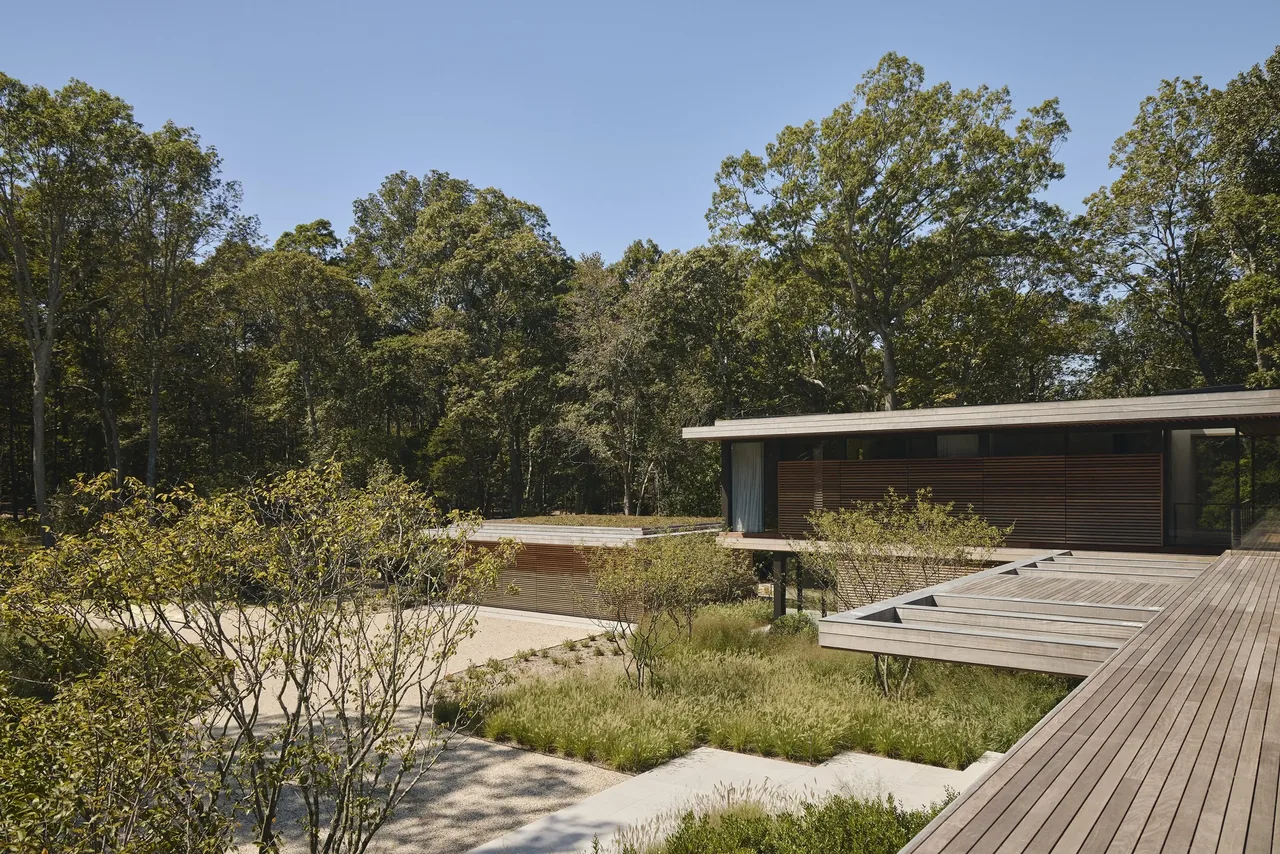 The FOREST EDGE project features a modern home with wood siding and integrated landscaping surrounded by mature trees.