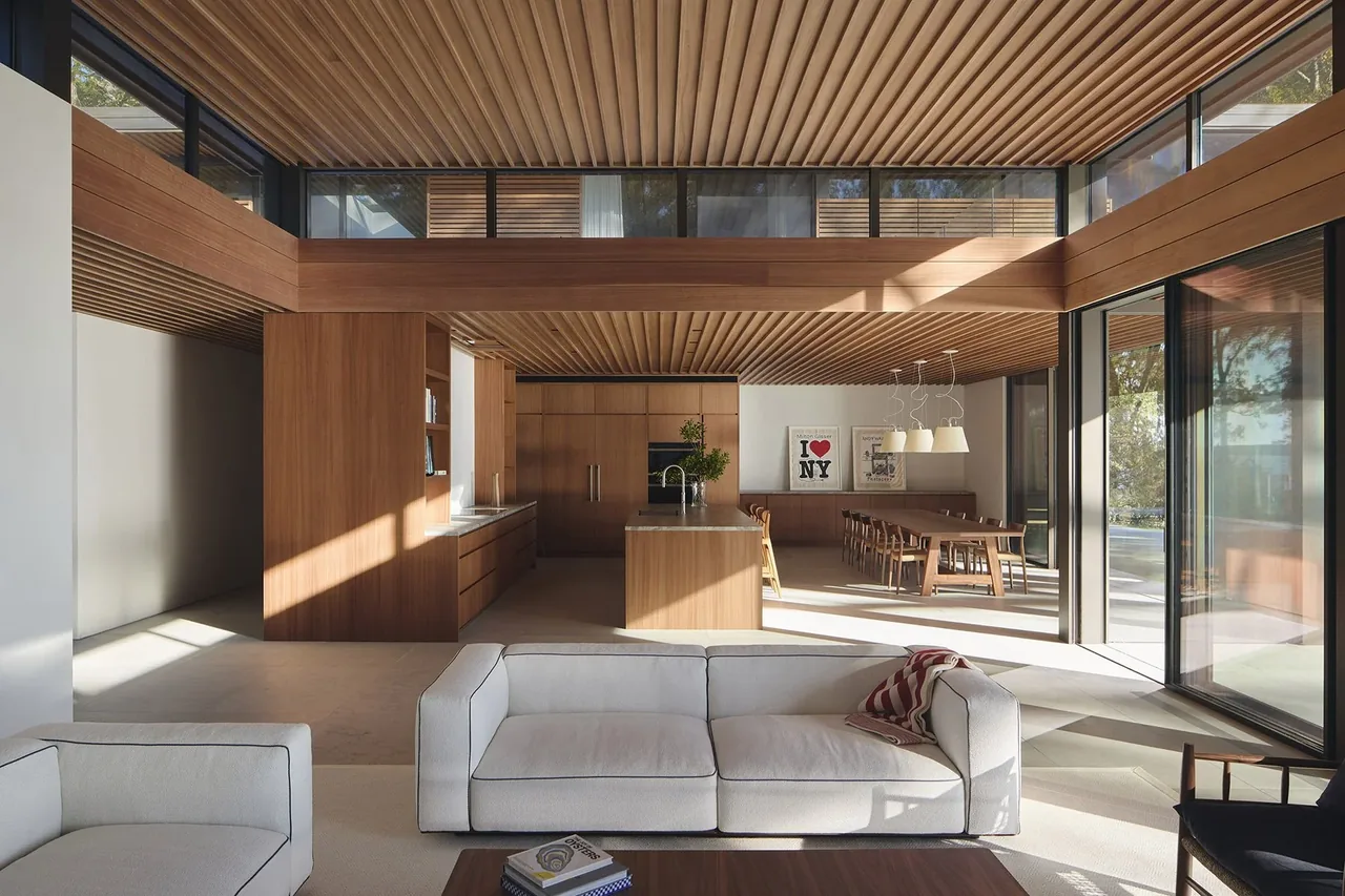 Open living and dining space with wood slat ceiling and integrated kitchen island in the FOREST EDGE project.