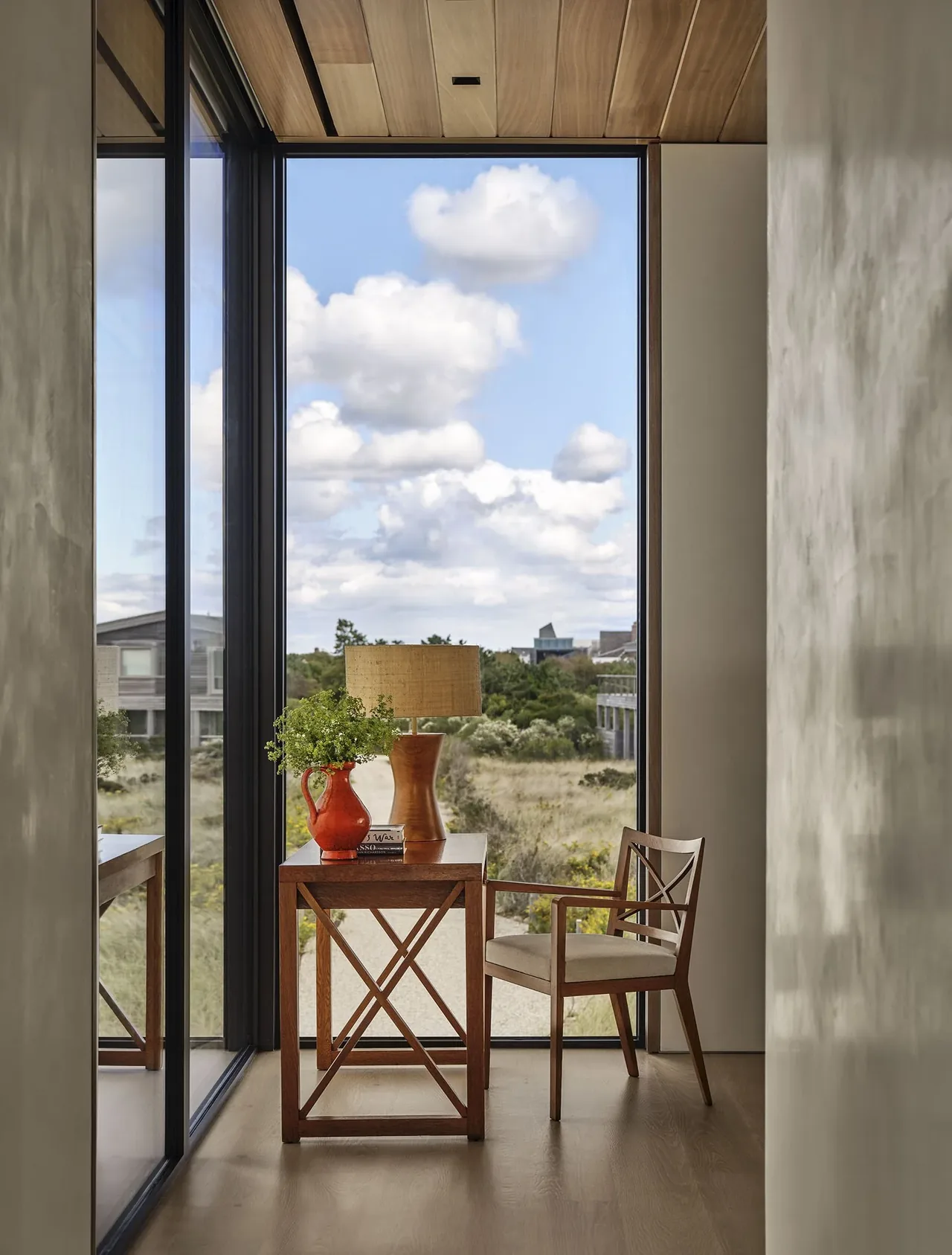 Cozy corner with wooden furniture and a large floor-to-ceiling window showcasing the outdoor landscape.