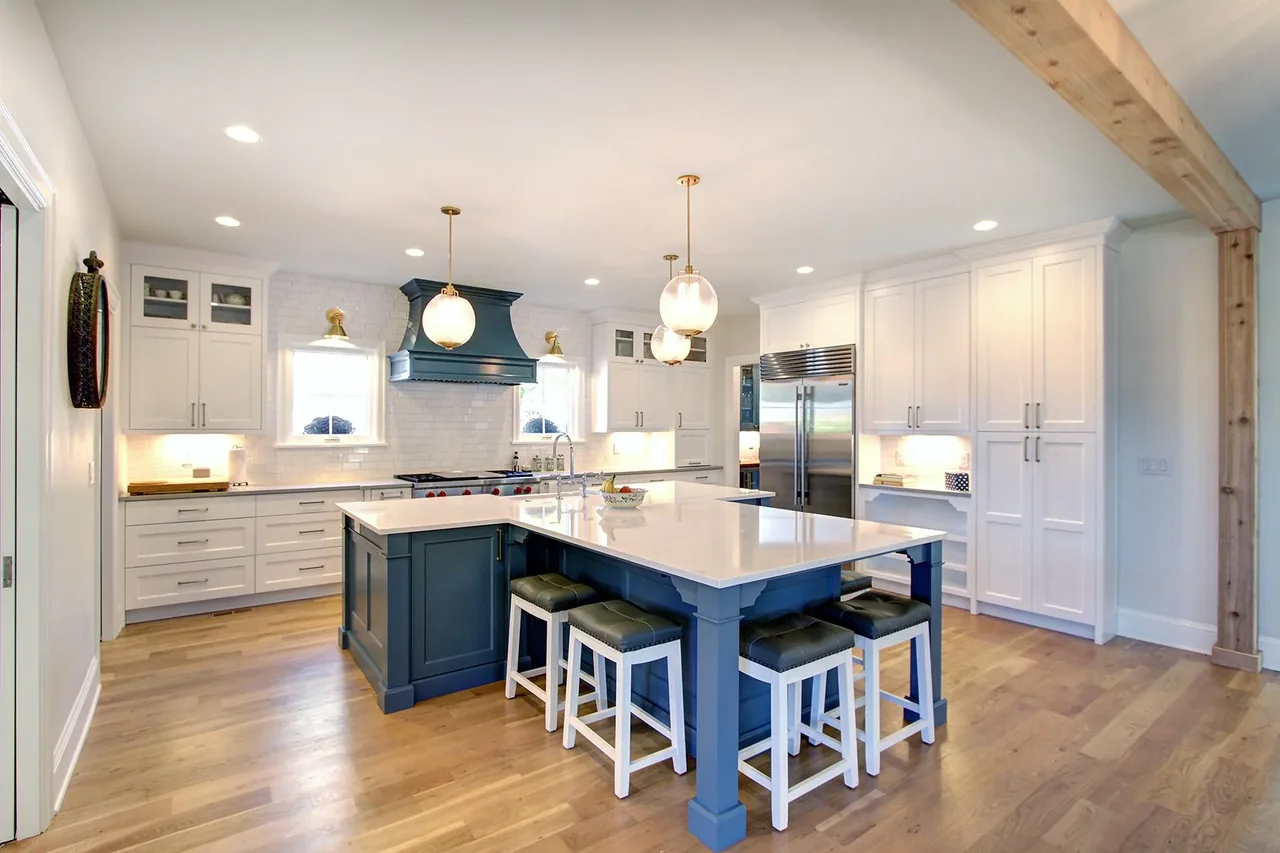 Transitional kitchen remodel with a blue island, white cabinets, and hardwood flooring.