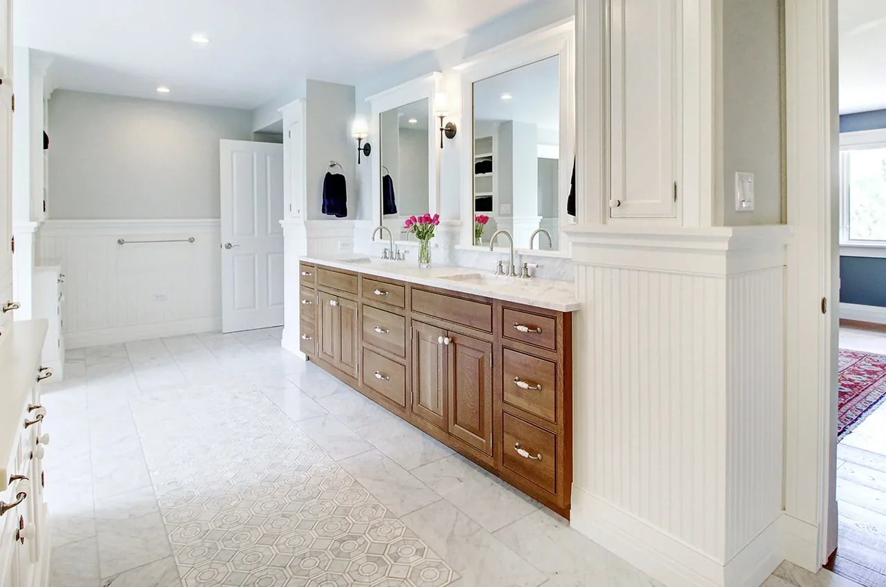The bathroom features a dual-sink vanity with wooden cabinets, marble countertop, and white beadboard wainscoting under gray paint.