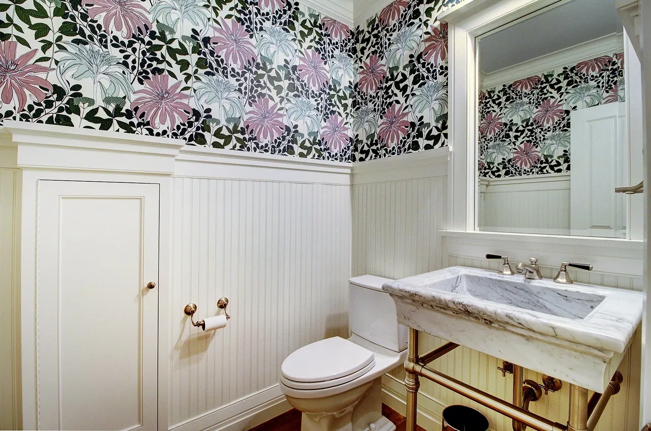 Powder bathroom with floral wallpaper and a marble sink in a remodeled transitional country home.