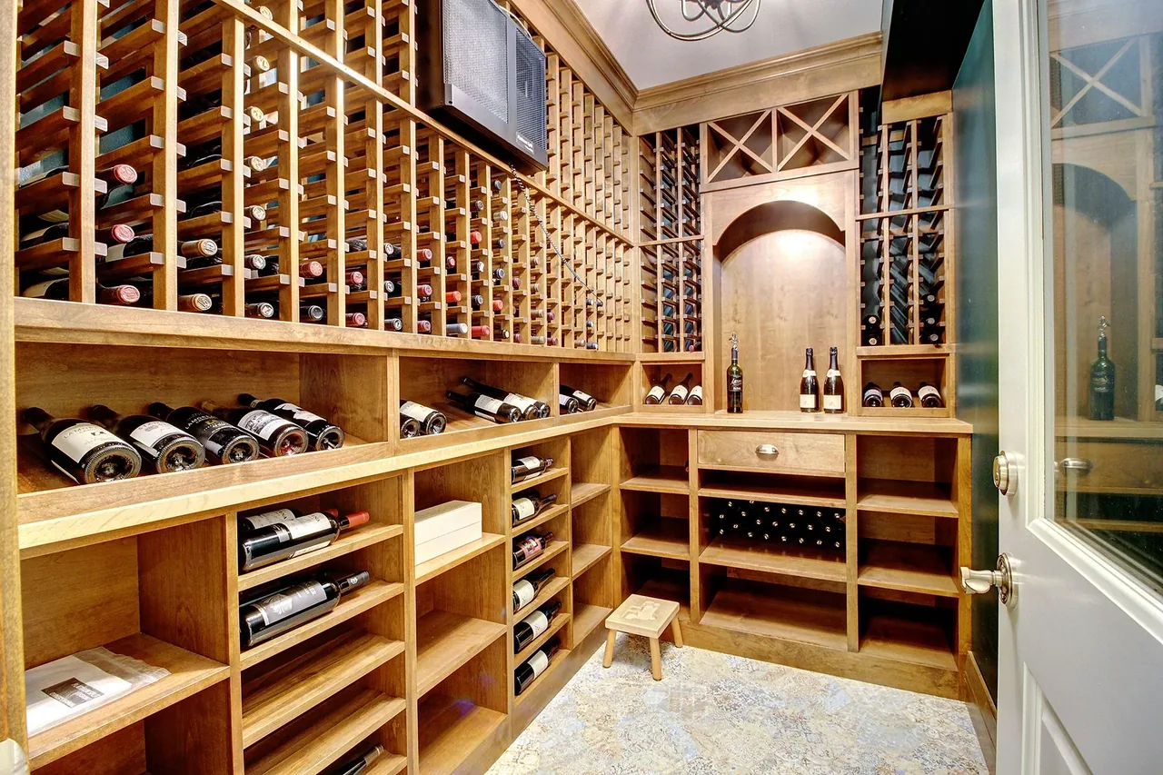 Wood-paneled wine storage room with numerous wooden racks and open shelving for wine bottles.