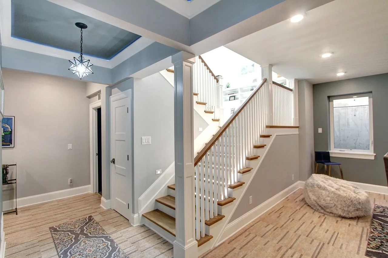 Entry hall with a wood-staircase featuring white railings, light wood flooring, and a decorative hanging star-shaped pendant light.
